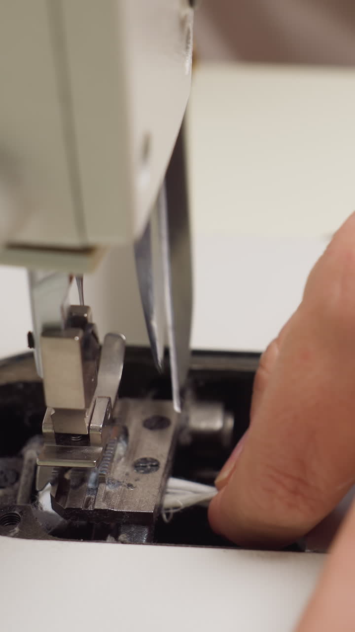 Precision sewing process, Hands guiding fabric smoothly, Worker maintains steady rhythm during stitch formation, Closeup of hands controlling fabric beneath presser foot during sewing task
