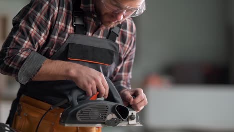 close-up portrait of a carpenter using an electric plane