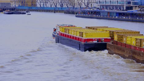 Un-Pequeño-Remolcador-Remolcando-Tres-Barcazas-Llenas-De-Contenedores-Bajo-El-Puente-De-La-Torre-Y-El-Río-Támesis-En-Londres