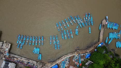 overhead drone shot of rows of fishing boats parked at the fish auction harbor - baron beach, yogyakarta, indonesia