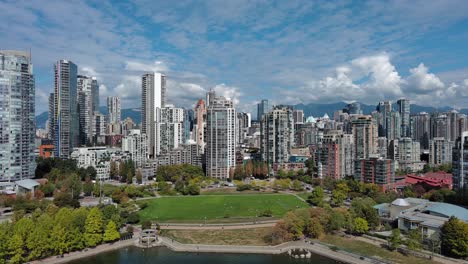 drone shot of david lam park and downtown vancouver in the summer with blue sky, kids playing in the park, buildings and the seawall