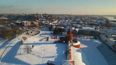 Drone-shot-of-the-historic-old-red-brick-Kaunas-Castle-in-Kaunas-old-town,-Lithuania-during-cold-snowy-winter