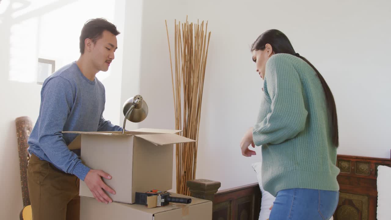 video de una feliz pareja diversa desempaquetando cajas después de mudarse