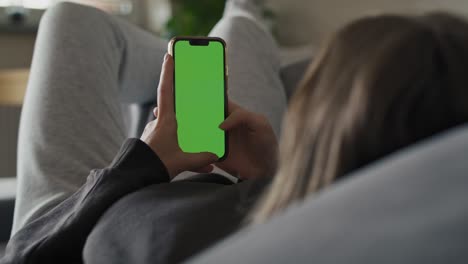 mujer caucásica acostada en el sofá y usando el teléfono móvil.