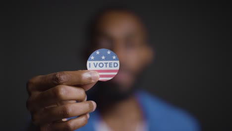 portrait of man holding i voted sticker in american election with pull focus