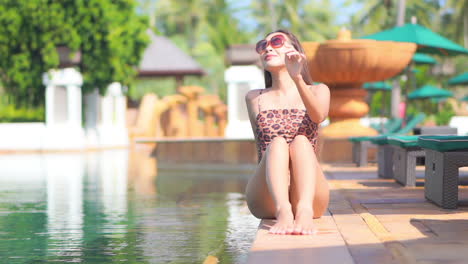 Mujer-Americana-En-Traje-De-Baño-Manchado-Bronceado-Sentado-En-El-Borde-De-La-Piscina-En-Un-Exótico-Hotel-Tropical-En-Hawaii