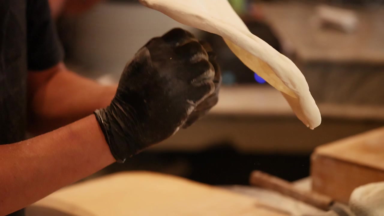Chef Stretching Pizza Dough in Professional Kitchen