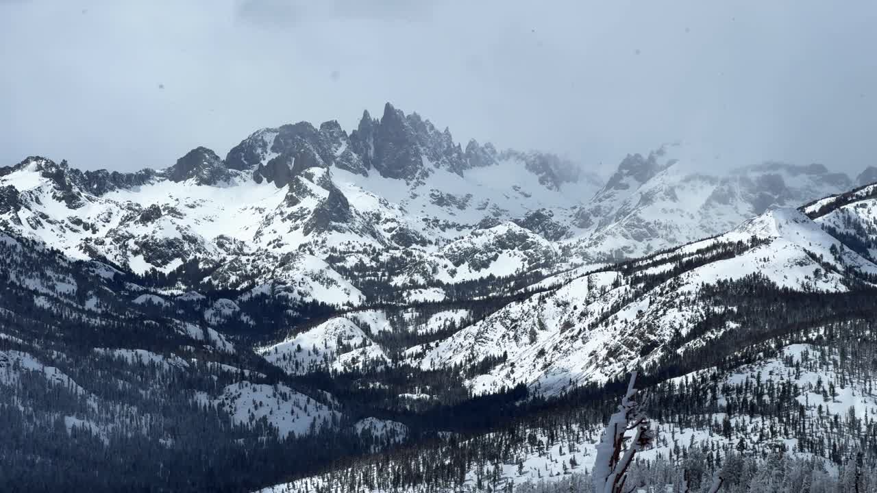 The Hemlocks Mammoth Mountain ski resort California winter spring blizzard deep powder snow misty fog foggy Minarets jagged peaks vista view chairlift gray clouds mystical sun pan left motion