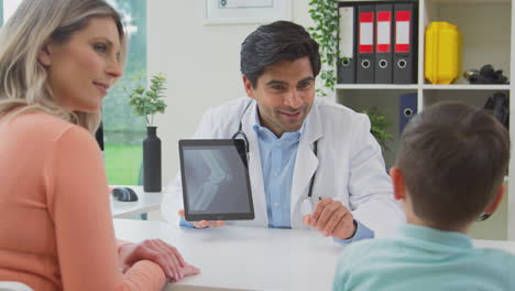 médico o médico de cabecera blanca reuniendo a madre e hijo para una cita mirando el escáner en la tableta digital