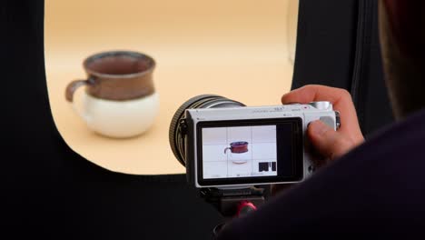 man taking photos of coffee cup in a light box