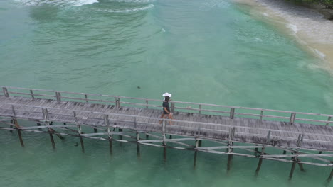 couple walking on wooden pier over turquoise water