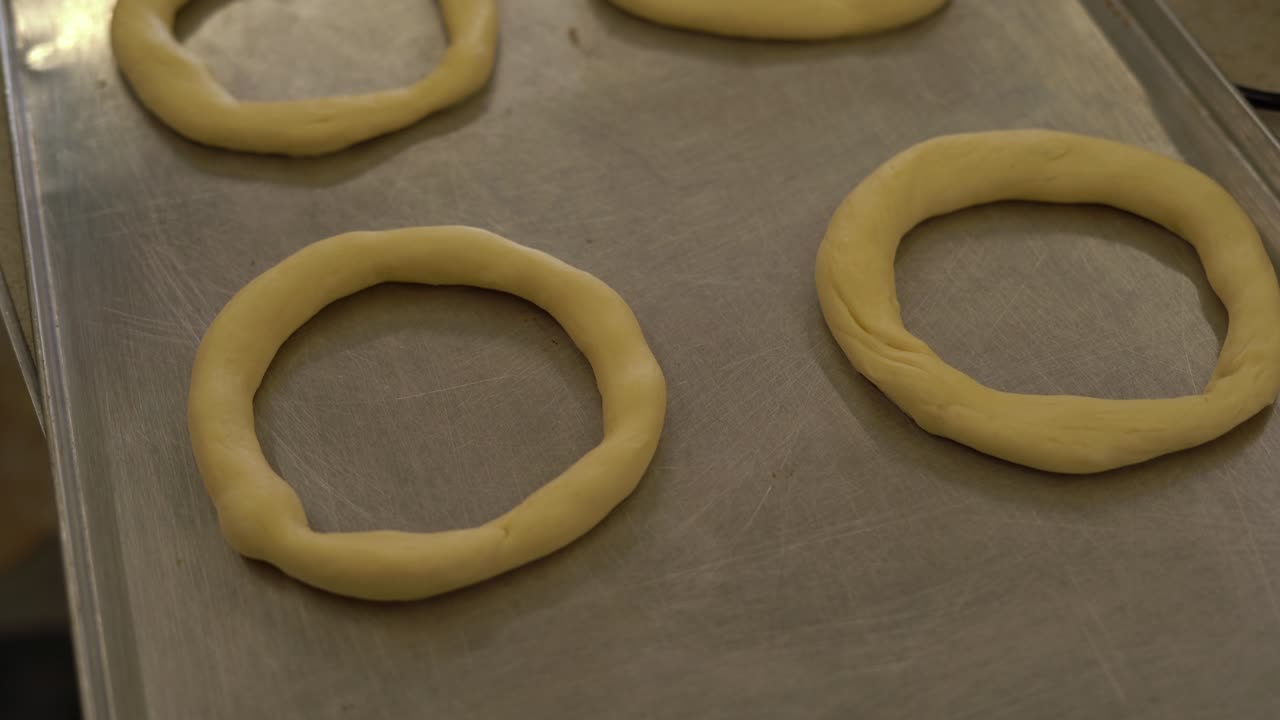 Primo piano sull'impasto dei bagel. Bagel crudi. Le mani dello chef li dispongono uno accanto all'altro