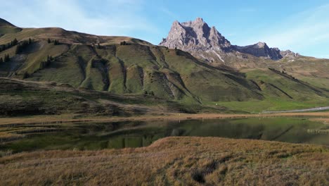 Zoom-in-shot-of-a-grassland-with-high-mountain-summits-and-water-puddle-in-the-middle-of-the-frame