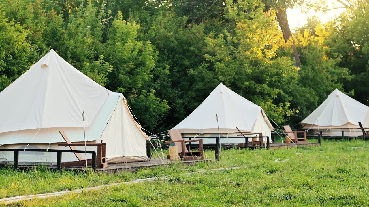 Tende con sedie in legno al glamping, foresta lussureggiante circostante