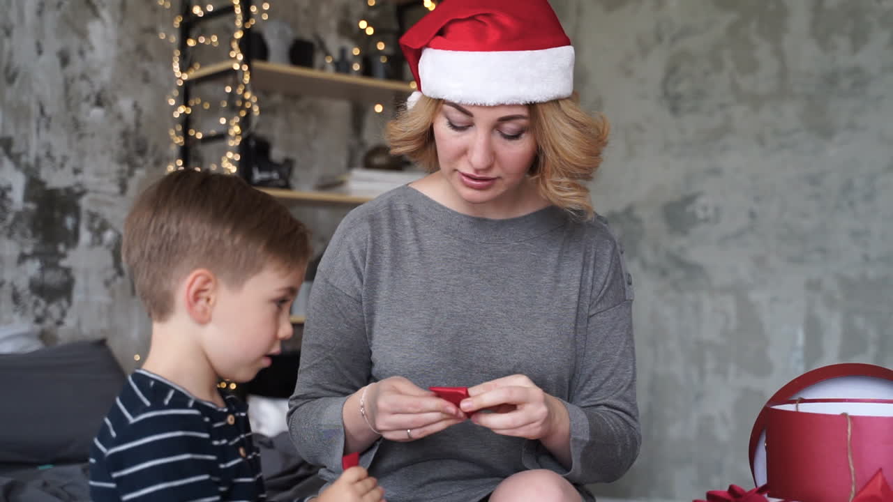 madre e hijo preparan cintas de regalos de navidad