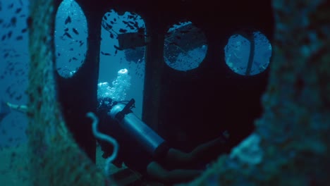 scuba divers explore a shipwreck underwater