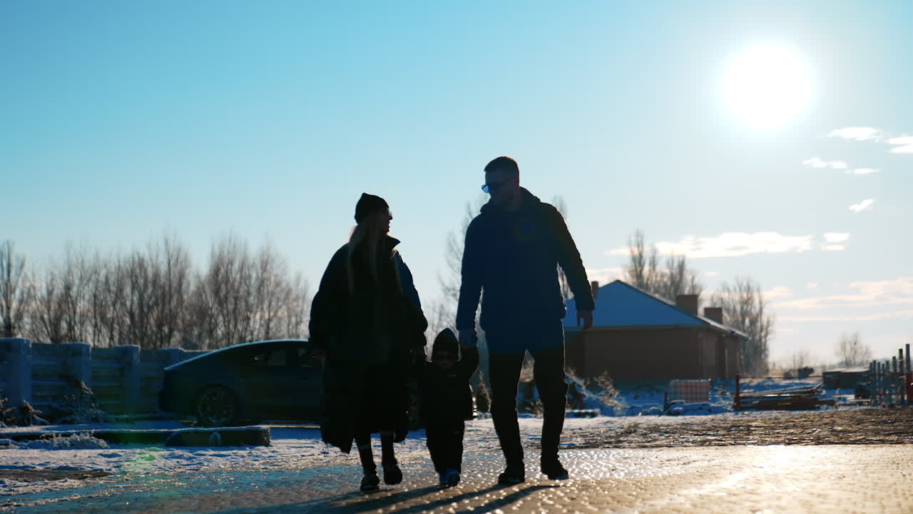 Family of three holding by the hands approaching camera. Portrait of a happy parents and little toddler son on the walk in winter.