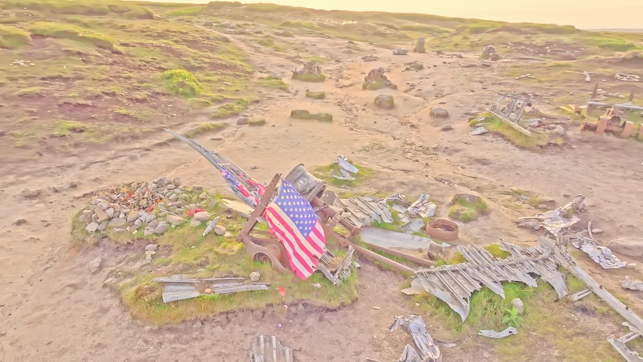 Aerial orbit over memorial stone grave at the B-29 Superfortress WWII plane crash site in the Peak District, England. American flag waving in the wind over historic site.