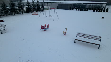 Aerial-Reveal-Of-A-Dog-Strolling-On-Snowy-Playground-In-Lubawa,-Poland,-During-Winter