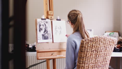 view through door of female teenage artist at easel drawing picture of dog in charcoal