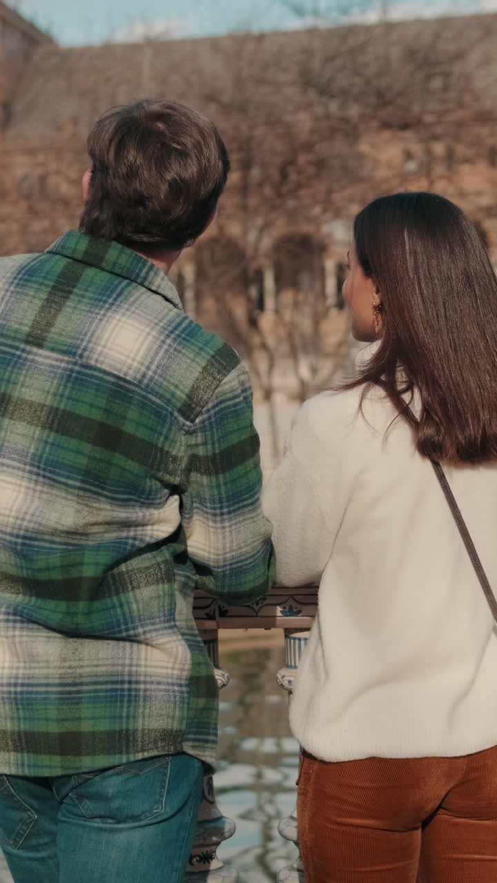 Happy young couple man and woman talking while standing on bridge