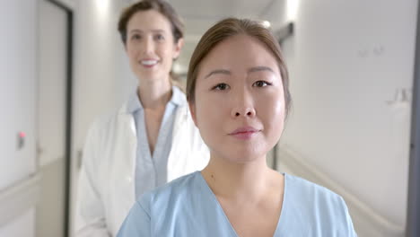 portrait of happy diverse female doctors standing in hospital corridor, selective focus, slow motion