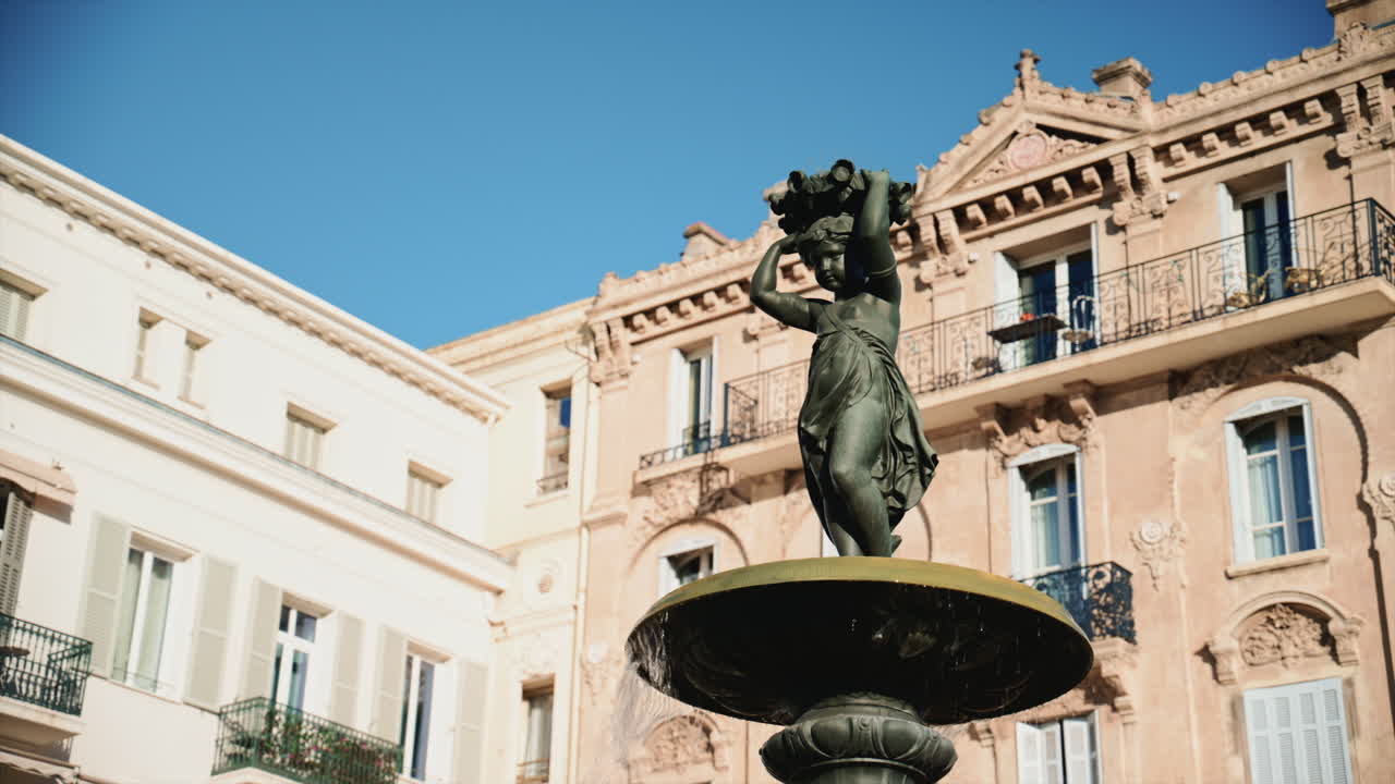 Primo piano di una statua di fontana in bronzo con acqua che scorre, circondata dall'architettura classica in Place du General de Gaulle