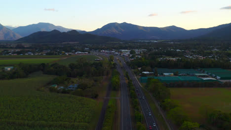 Vehículos-Que-Viajan-Por-Una-Carretera-Escénica-Entre-Campos-Verdes-En-Cairns,-Queensland,-Australia---Toma-Aérea-De-Drones