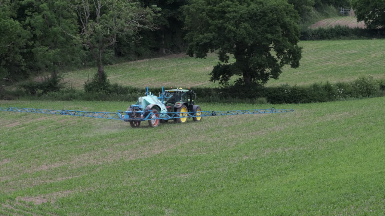 un equipo de pulverización de remolque de tractor rocía un campo de laberinto recién plantado en un campo en warwickshire, reino unido