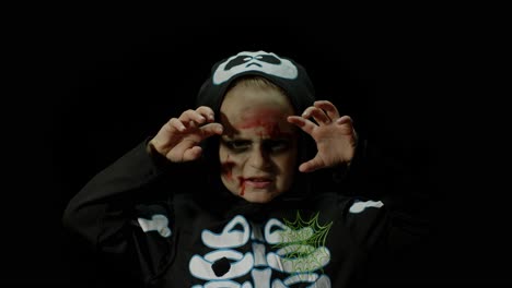 halloween, angry girl with blood makeup on face. kid dressed as scary skeleton, posing, making faces