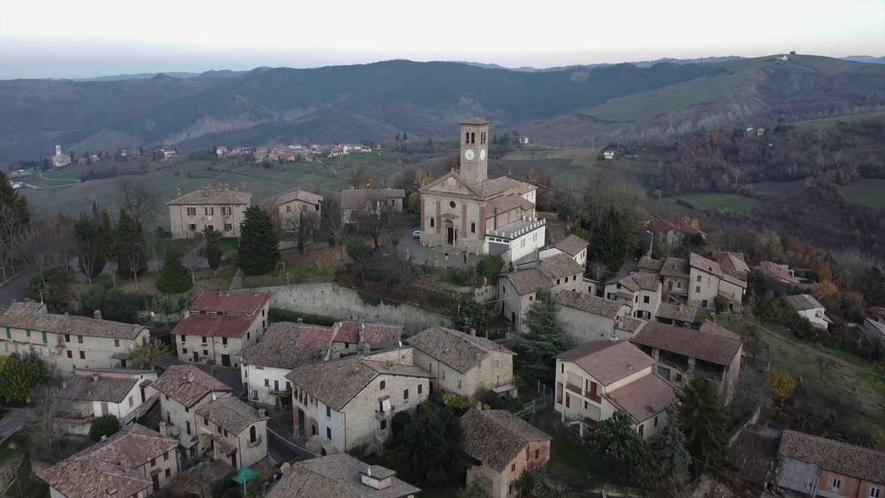 Aerial shot backward from ancient church over a historic town of Fortunago in Italy