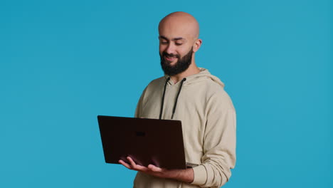 Young-adult-waving-at-videocall-connection-on-laptop