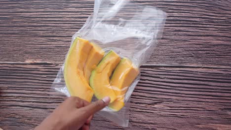 hand holding a plastic bag of sliced pumpkin