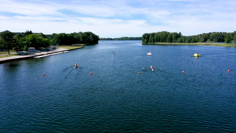 aerial: following shot of kayaking athletes in paddling canoes on the surface of the lake racing towards