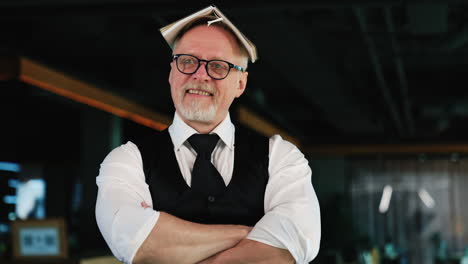 adult man wearing glasses puts the paper notebook on his head. businessman fooling around in office. close up.
