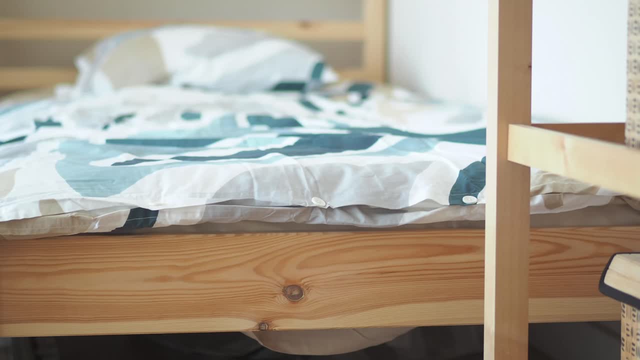 A close-up view of a wooden bed frame with a patterned duvet