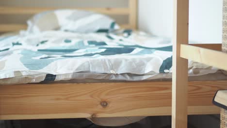 A close-up view of a wooden bed frame with a patterned duvet