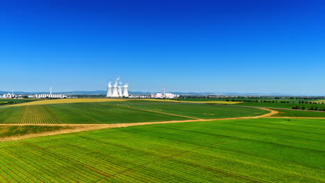 power plant surrounded by green fields. a modern power plant stands near lush green fields under a clear blue sky, showcasing energy production and agriculture