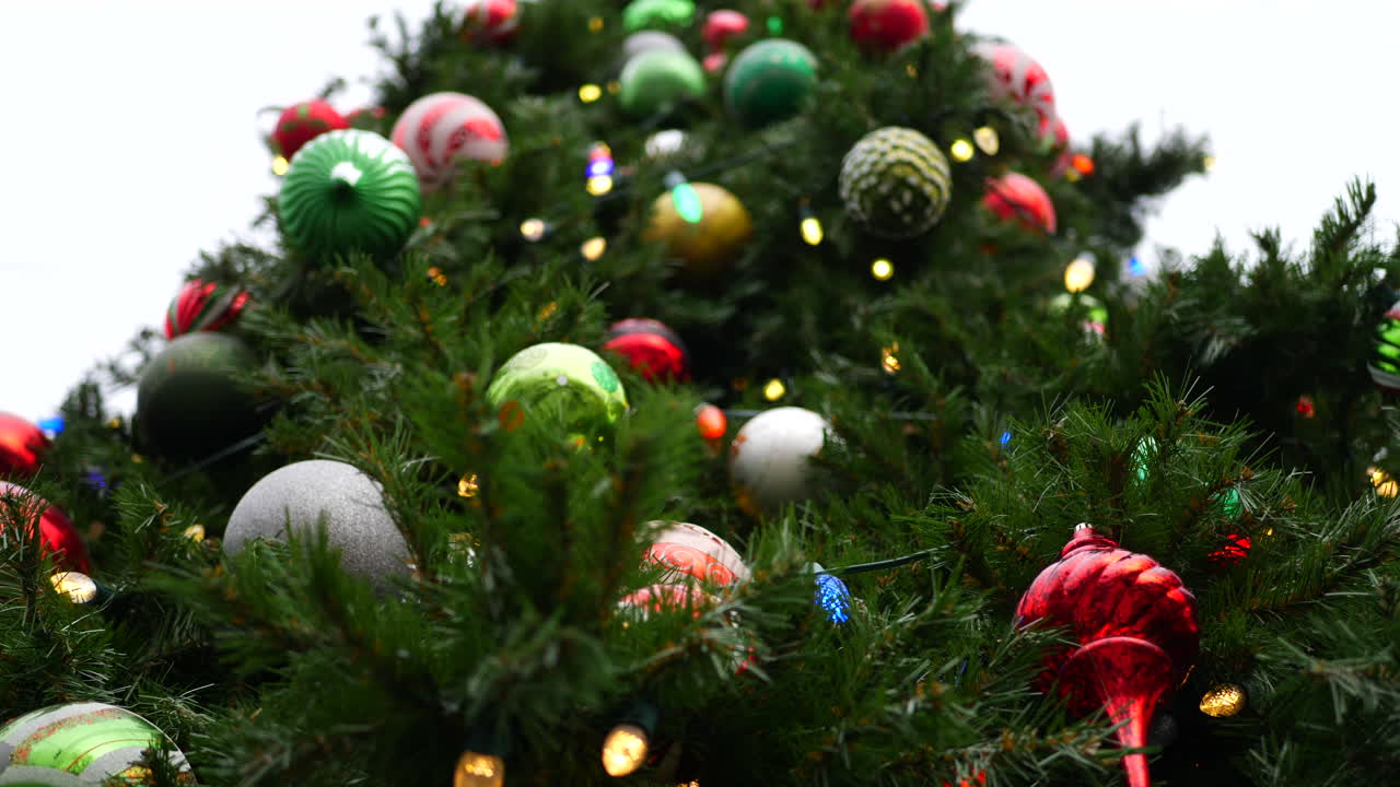 A huge tall Christmas tree background with many festive holiday ornaments, lights and decorations