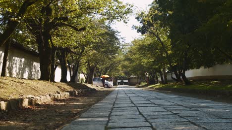 Slide-shot-of-a-stone-path-in-a-temple-with-peoeple-in-the-distance-in-Kyoto,-Japan-4K-slow-motion