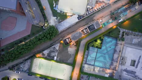 aerial drone shot at night showing premium housing complex with sports facilitites consisting of swimming pool, hockey area and basket ball court showing the rapid development of real estate