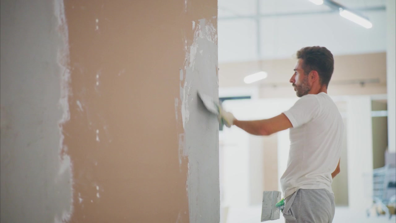 Construction Worker Applying Plaster to Wall in Interior Renovation