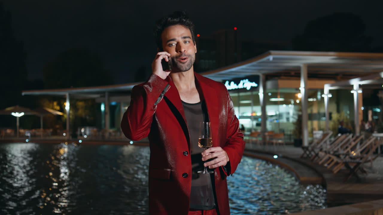 Glamorøs mann ringer med smarttelefon på en bassengfest om natten, nærbilde.