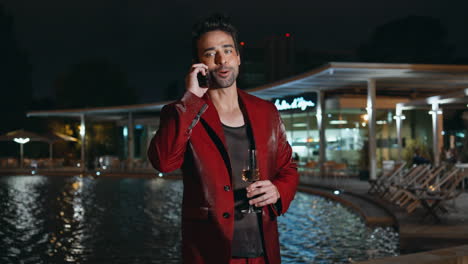 glamorous guy calling smartphone at poolside party night close up. latin macho