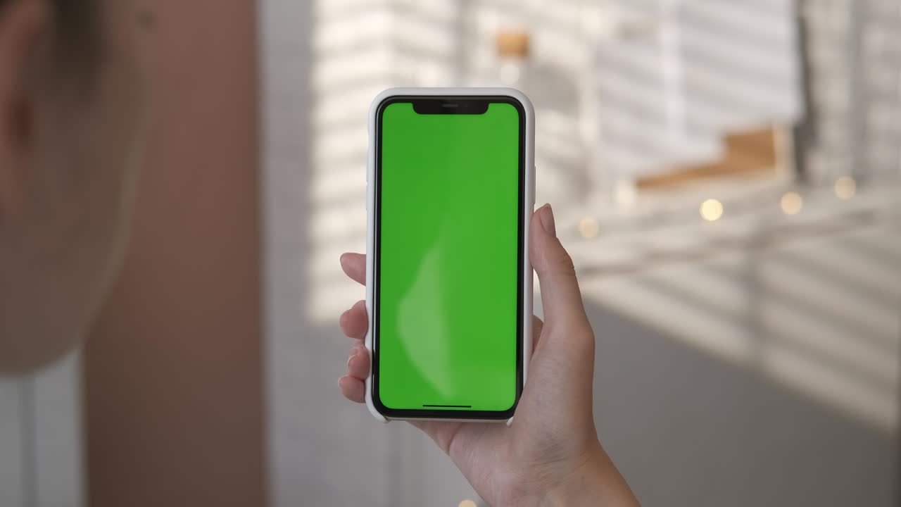 chica usando un teléfono inteligente con pantalla verde en la sala de estar