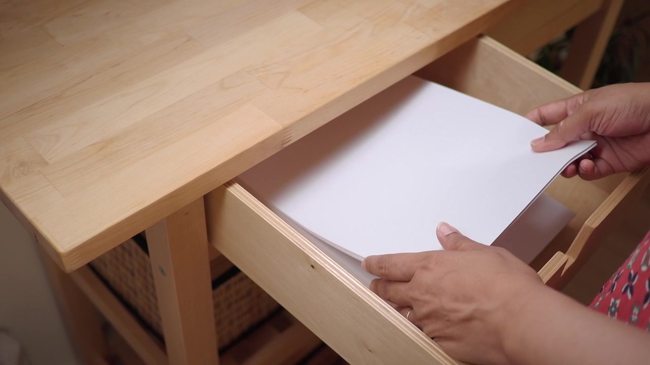 Person Opening Wooden Drawer and Taking Out Stack of Paper