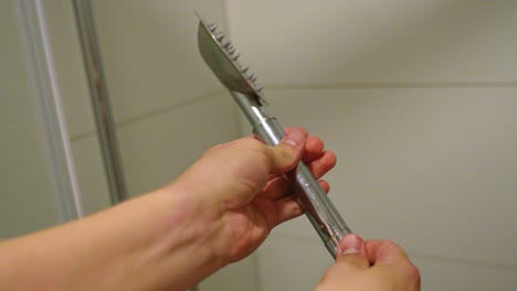 man's hands fitting dirty shower head with limescale to hose, close-up