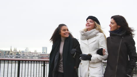 female friends walk along south bank on winter visit to london