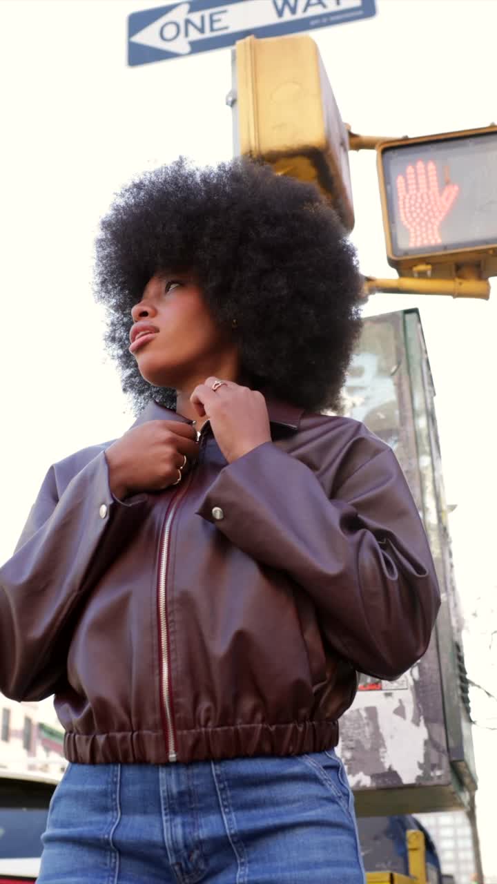 Woman in a brown jacket and jeans on a city street