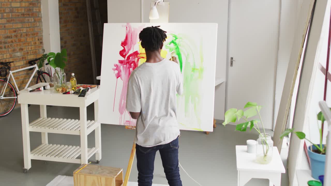 아트 스튜디오 에서 캔버스 에 그림 을 그리는 아프리카계 미국인 남성 예술가 의 뒷면